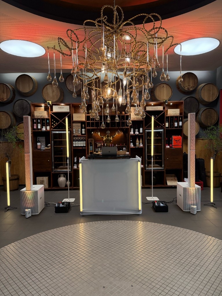Weißes Hochzeits-DJ-Setup mit Ambientebeleuchtung in einer Weinkeller-Location